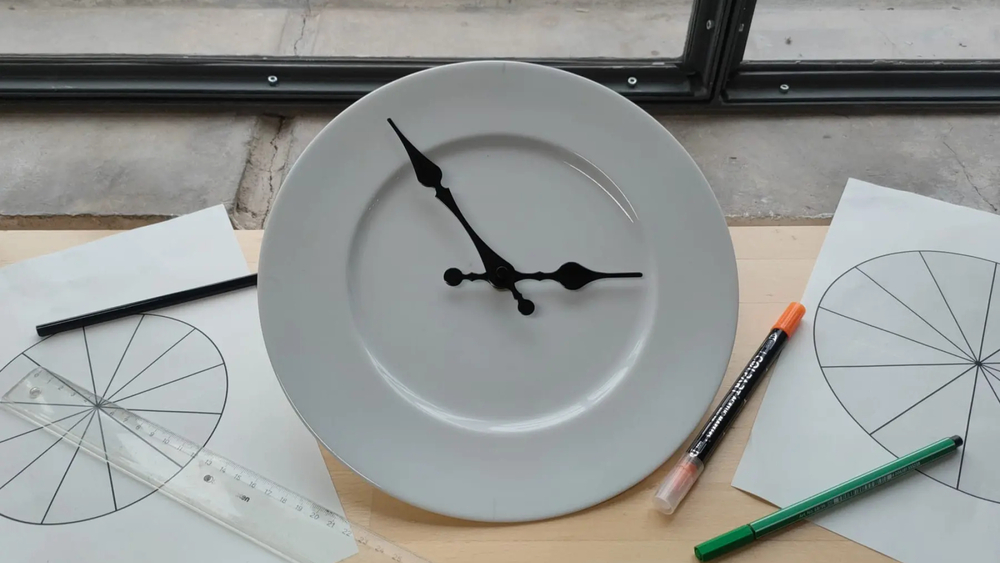 Ein Teller mit Uhrzeigern inmitten von Zeichengeräten und Diagrammen.