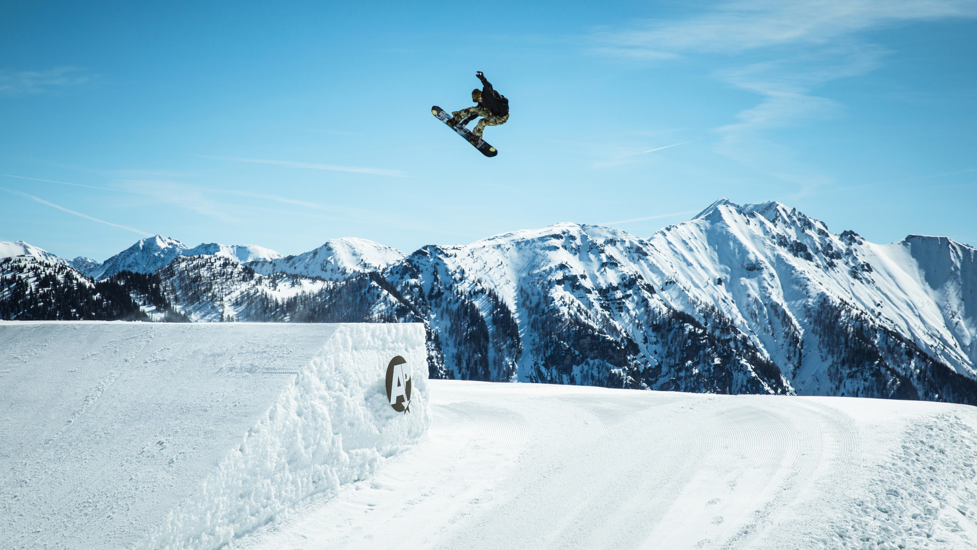 Snowboarder führt einen Sprung in einer verschneiten Berglandschaft aus.