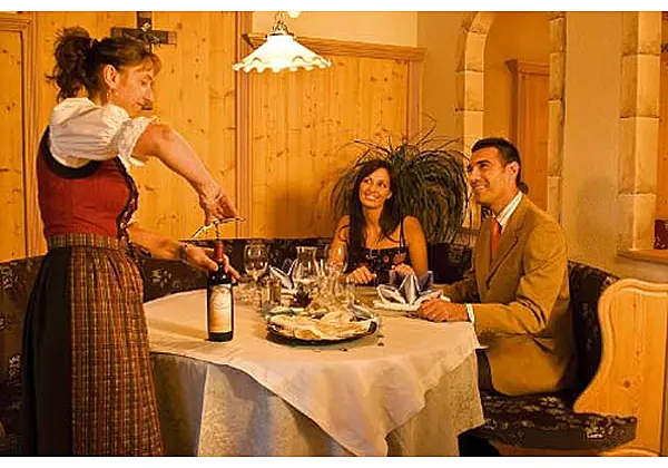 Eine Servicekraft öffnet einem Pärchen am Tisch eine Flasche Wein im Restaurant vom  Hotel Tonnerhof