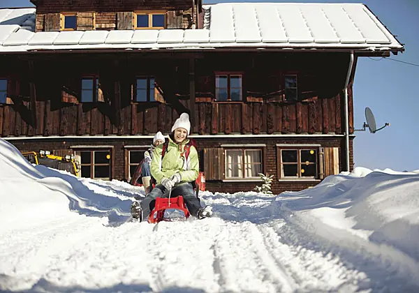 Zwei Frauen mit Rodeln auf der Naturrodelstrecke an der Wannenkopfhütte