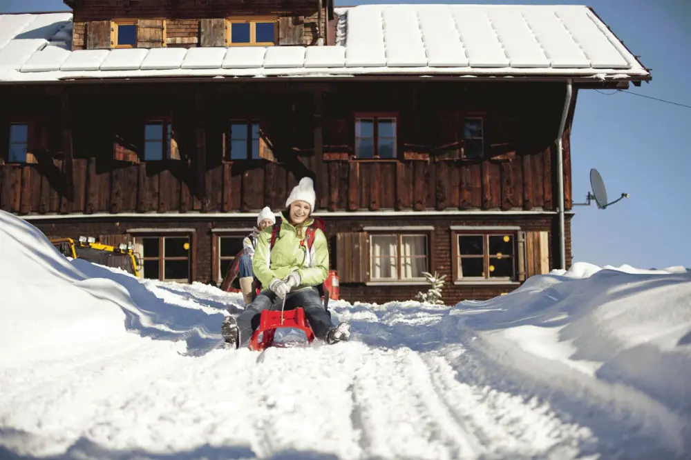 Zwei Frauen mit Rodeln auf der Naturrodelstrecke an der Wannenkopfhütte